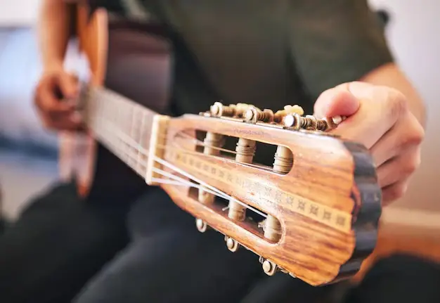 Hombre Afinando una Guitarra